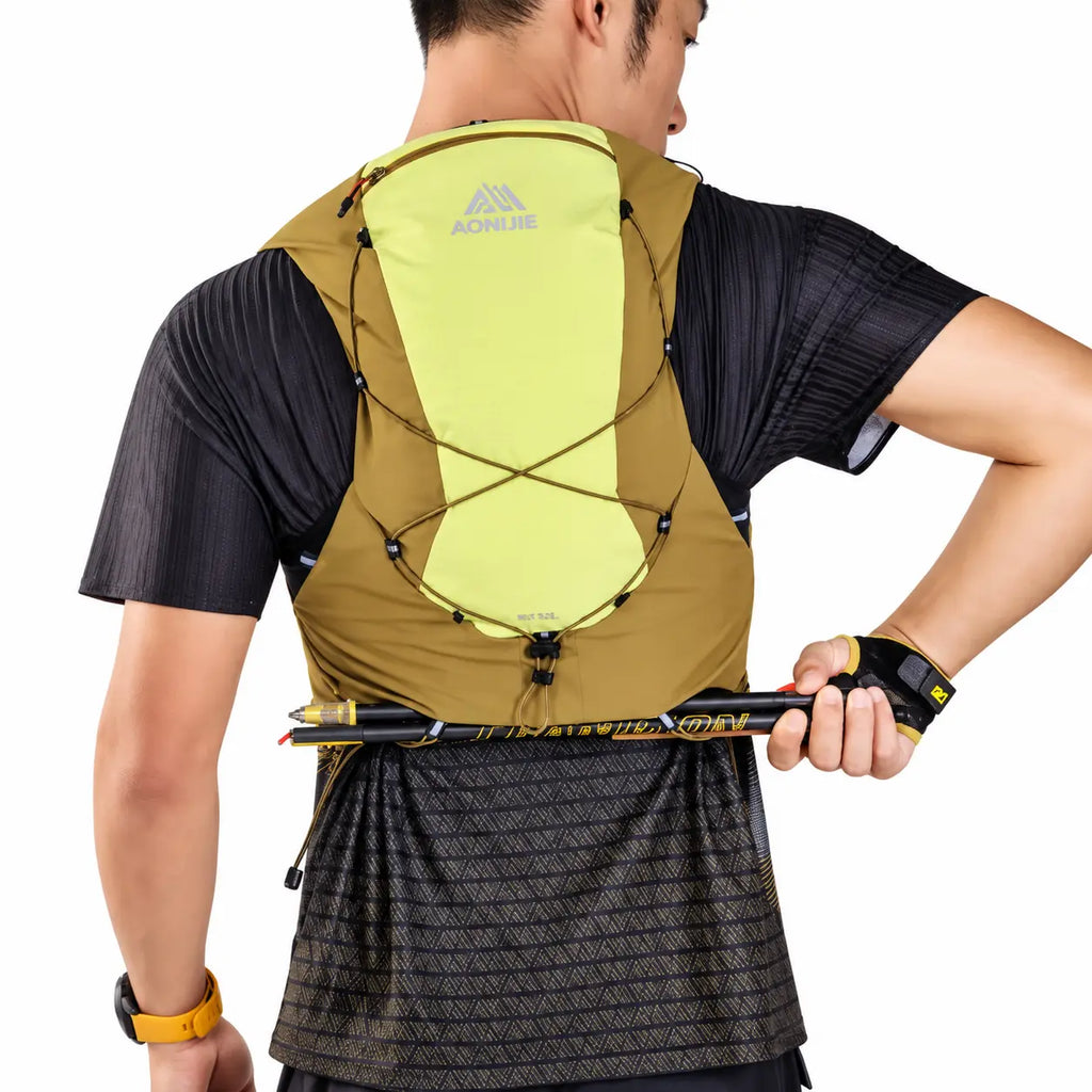 sac ultra trail 12L de couleur jaune porté par un homme attrapants ses batons a l'arriere de son sac 